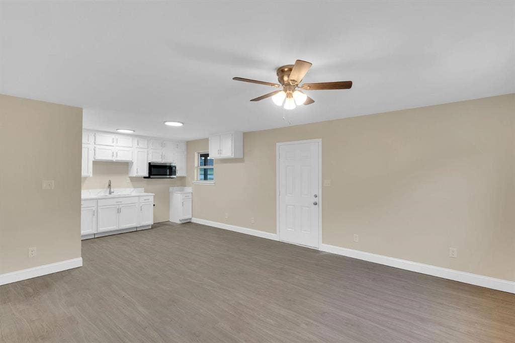 705 George Hopper Road, Midlothian, TX 76065 Kitchen area featuring white cabinetry, a built-in microwave, and a sink, complemented by wood-finish flooring and an overhead ceiling fan
