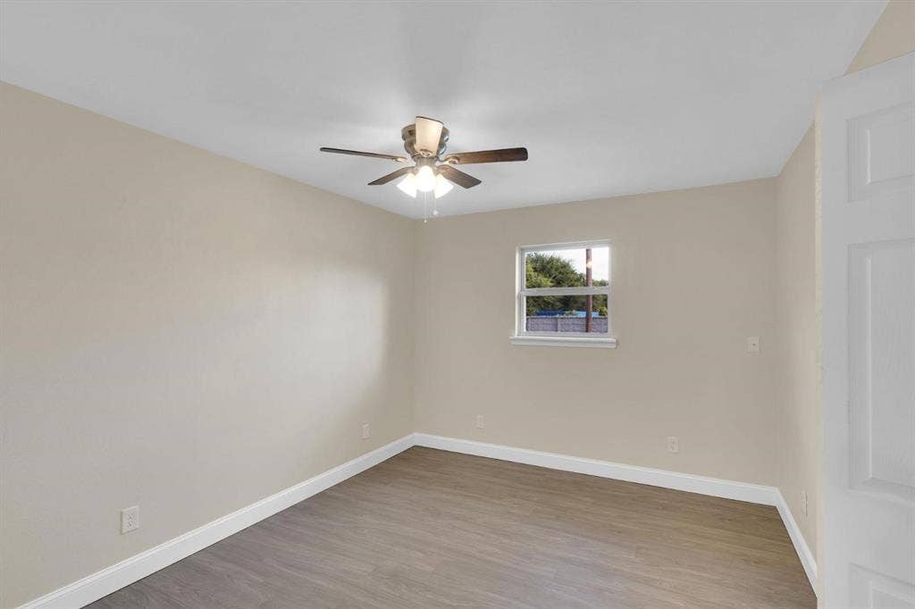 705 George Hopper Road, Midlothian, TX 76065 Neutral-toned room featuring wood-finish flooring, a central ceiling fan with integrated lighting, and a single-pane window