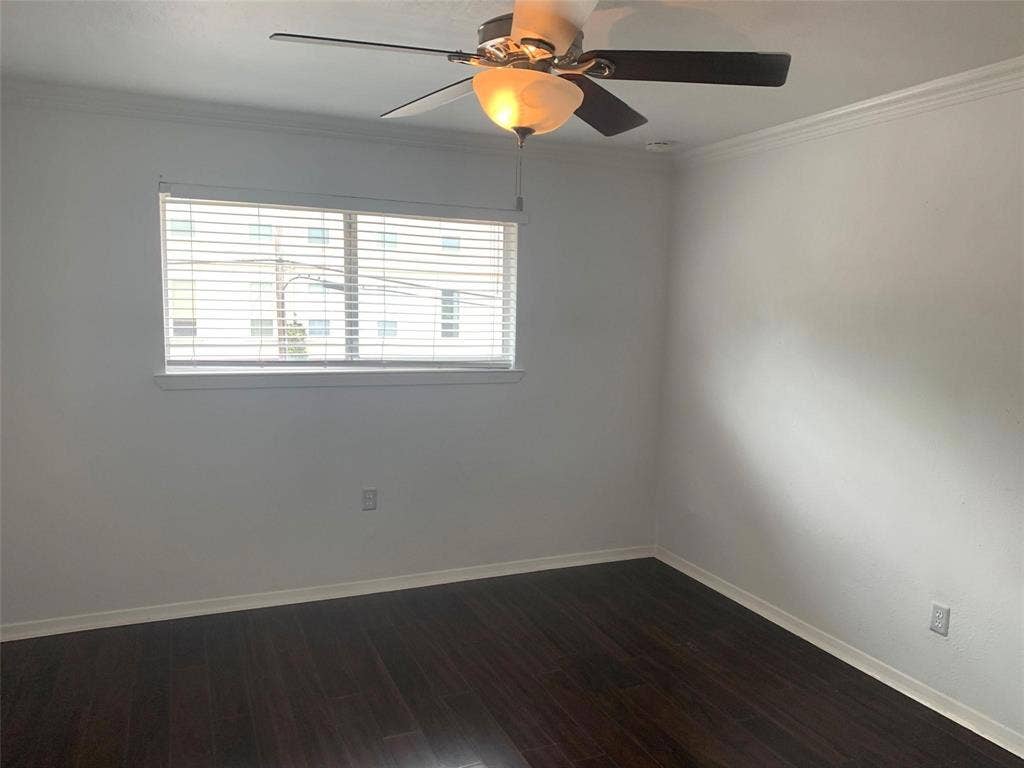 Dark wood-finish flooring, neutral wall tones, multi-blade ceiling fan with integrated lighting, and horizontal window blinds