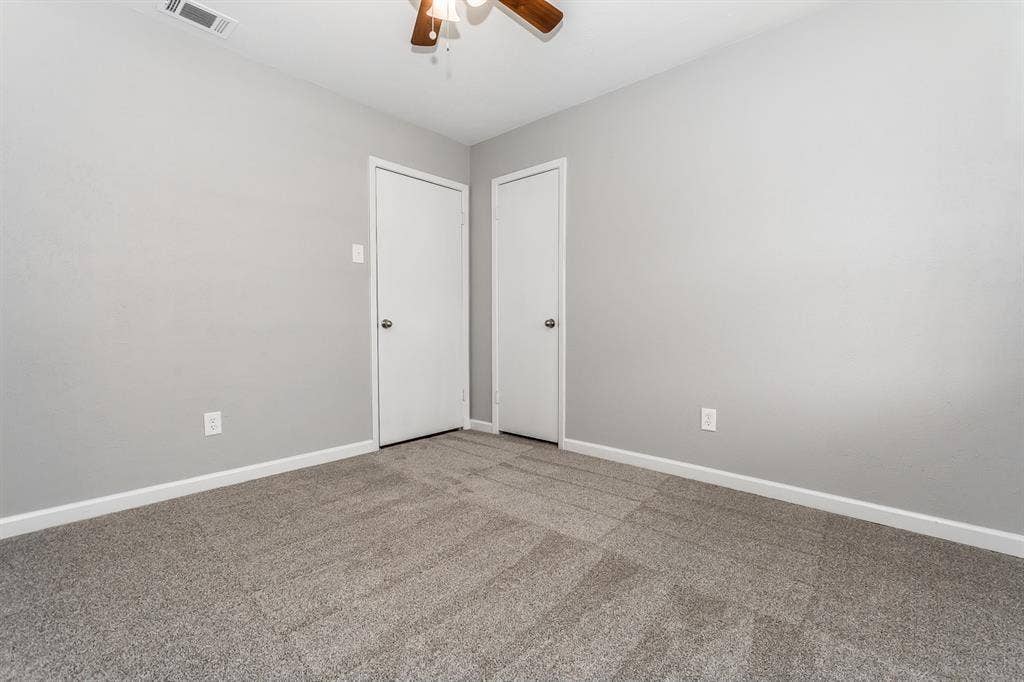 Neutral wall paint, textured wall-to-wall carpeting, and a ceiling fan with integrated lighting