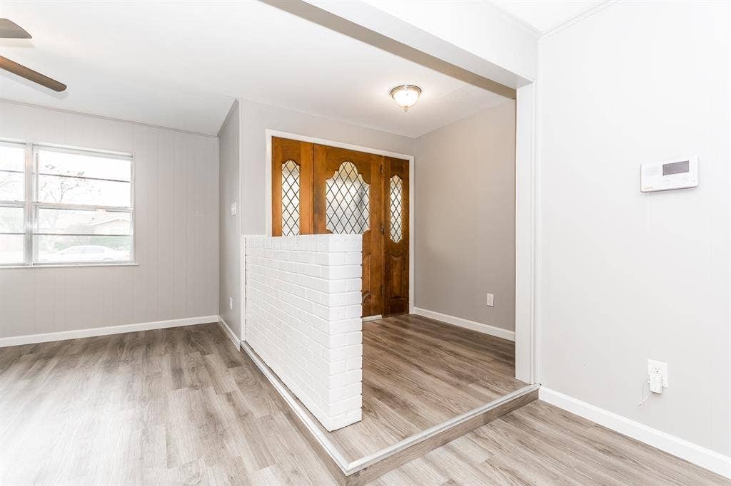 Entryway featuring a wood front door with diamond-patterned glass inserts, a white painted brick half-wall divider, wood-finish flooring, and a flush-mount ceiling light fixture