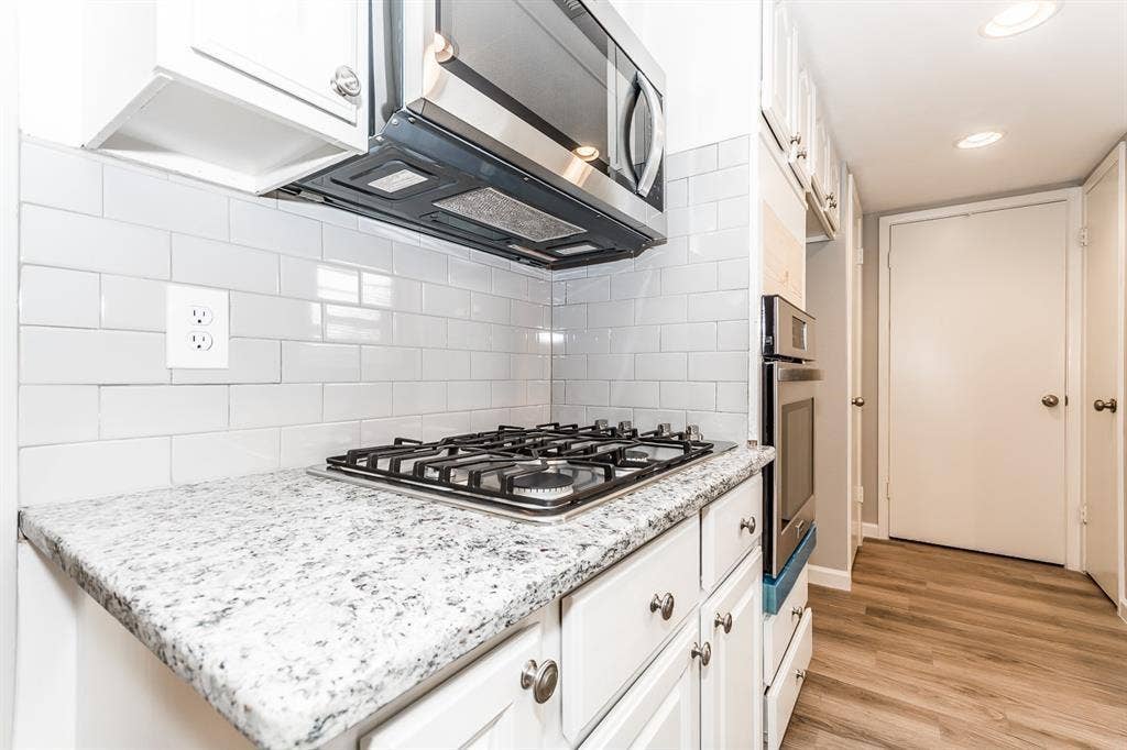 Kitchen featuring white cabinetry, stone-finish countertops, subway tile backsplash, stainless steel gas cooktop, and recessed lighting