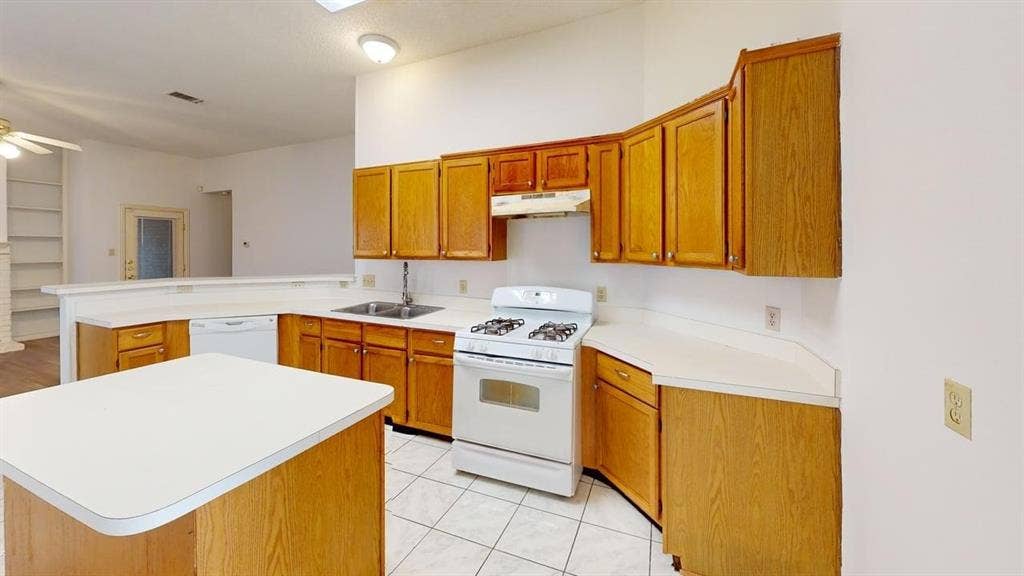 733 Rockett Lane, Cedar Hill, TX 75104 Kitchen featuring wood cabinetry, white countertops, a central island, a white gas range with overhead vent hood, and tile flooring