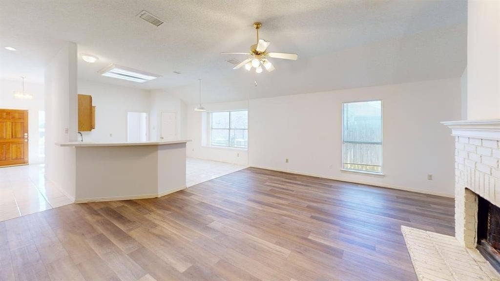 733 Rockett Lane, Cedar Hill, TX 75104 Open-concept living space featuring wood-finish flooring, vaulted ceilings, a brick fireplace, and a breakfast bar
