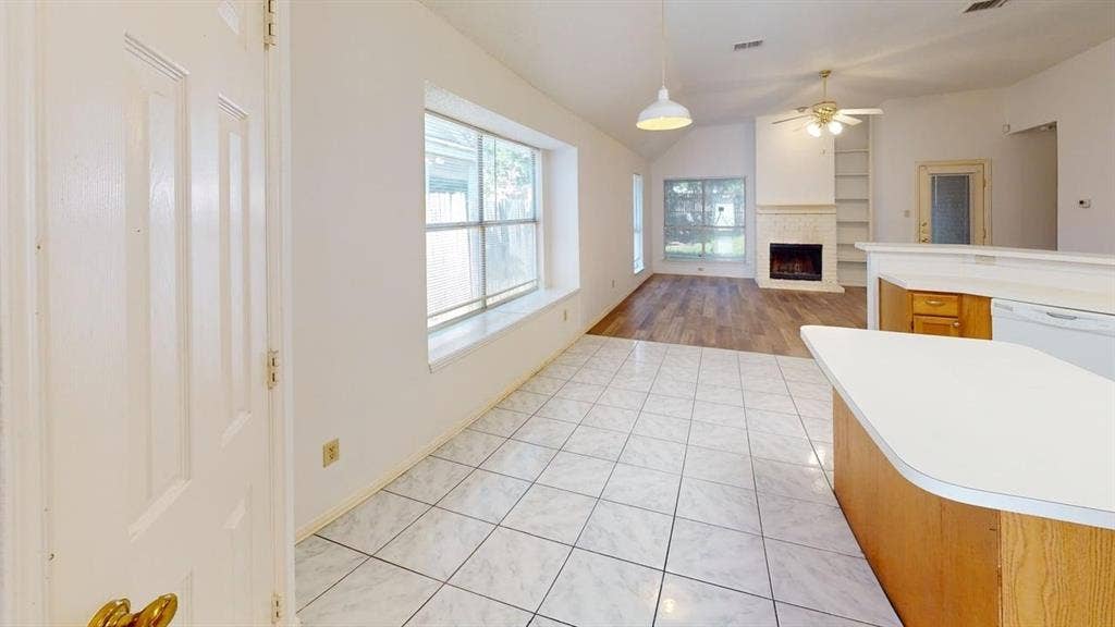 733 Rockett Lane, Cedar Hill, TX 75104 Open-concept interior featuring light tile flooring, wood-finish flooring, a fireplace with integrated shelving, and a peninsula kitchen counter