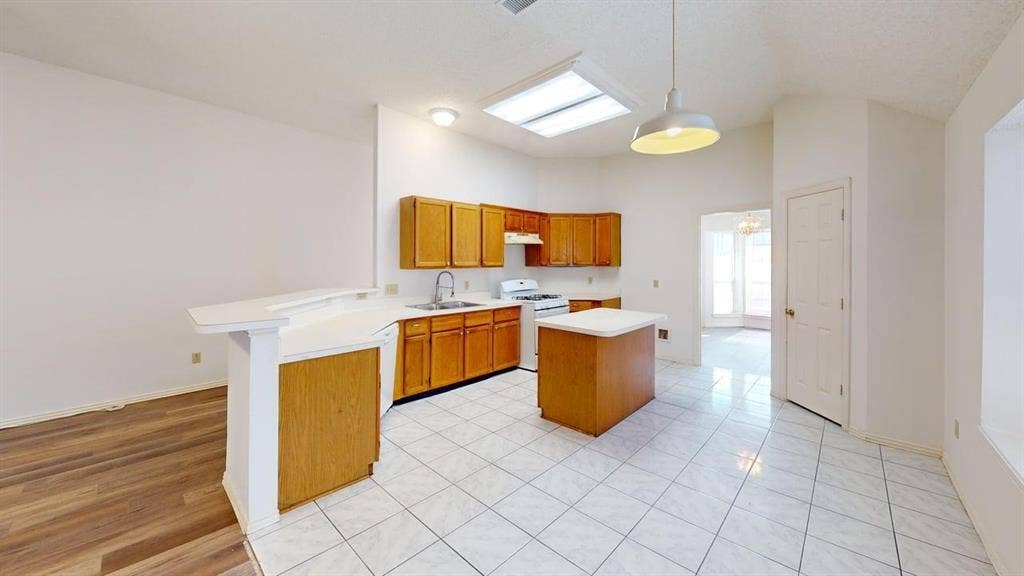 733 Rockett Lane, Cedar Hill, TX 75104 Kitchen featuring wood cabinetry, white countertops, a central island, tile flooring, and recessed ceiling lighting