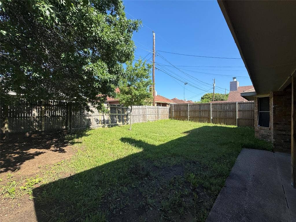 733 Rockett Lane, Cedar Hill, TX 75104 Rear exterior space featuring a concrete patio, wood privacy fencing, grass lawn, and mature trees