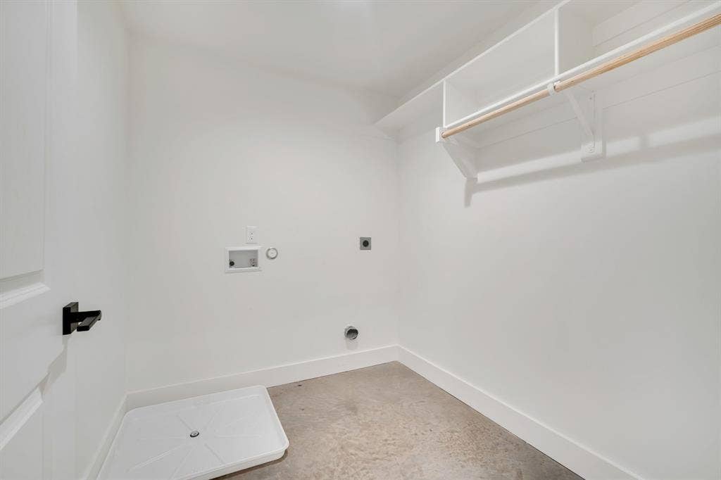 301 W Main Street, #252, Midlothian, TX 76065 Utility area featuring white built-in shelving, a wooden hanging rod, a white floor-mounted drainage pan, and a black lever-style door handle