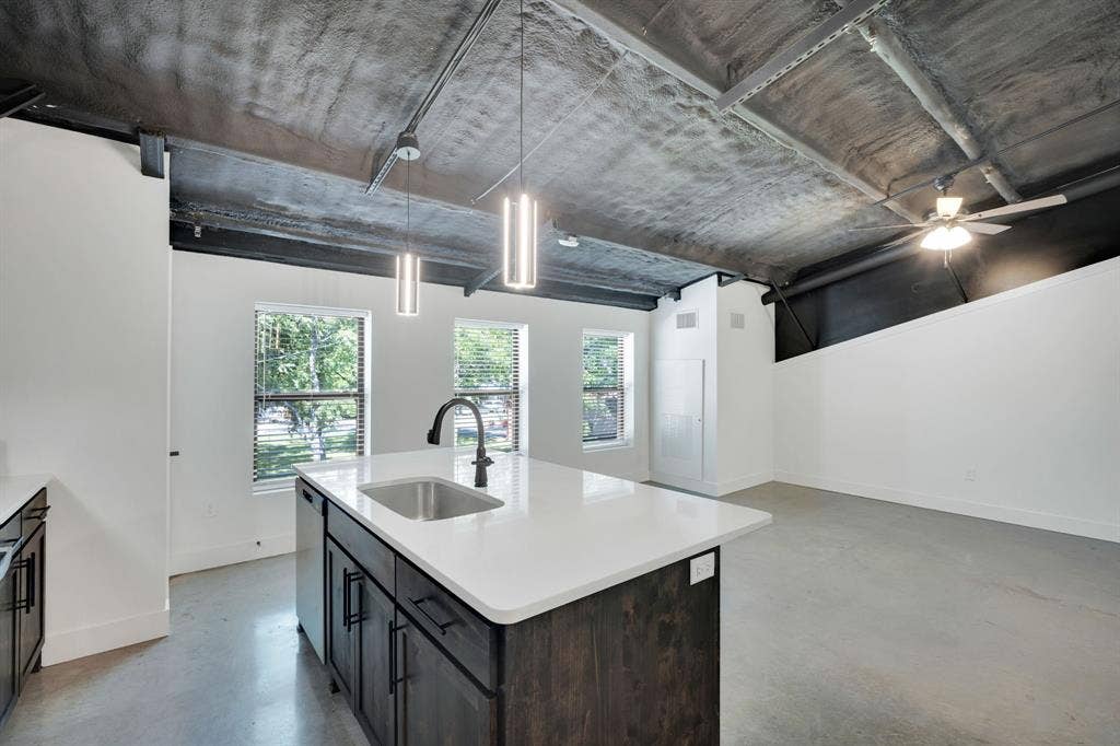 301 W Main Street, #252, Midlothian, TX 76065 Industrial-style interior featuring exposed concrete ceilings, a kitchen island with stone-surface countertop, dark-finish cabinetry, concrete flooring, and pendant lighting