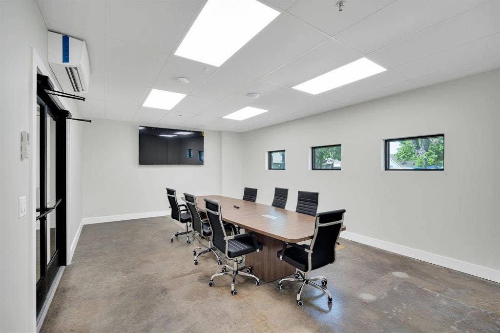 Polished concrete flooring, drop ceiling with recessed panel lighting, wall-mounted ductless climate control unit, and framed glass door