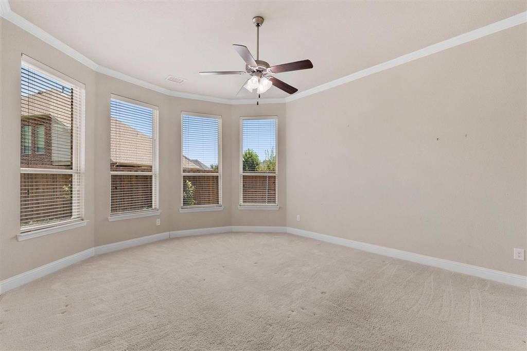 4109 Rainey Street, McKinney, TX 75070 Bay window architecture featuring four windows, neutral carpeting, crown molding, and a central ceiling fan with integrated lighting