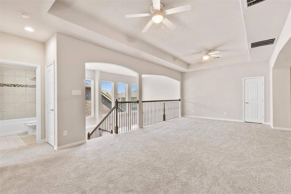 4109 Rainey Street, McKinney, TX 75070 Expansive upper level featuring a tray ceiling, dual ceiling fans, iron balustrade railing, and neutral wall-to-wall carpeting