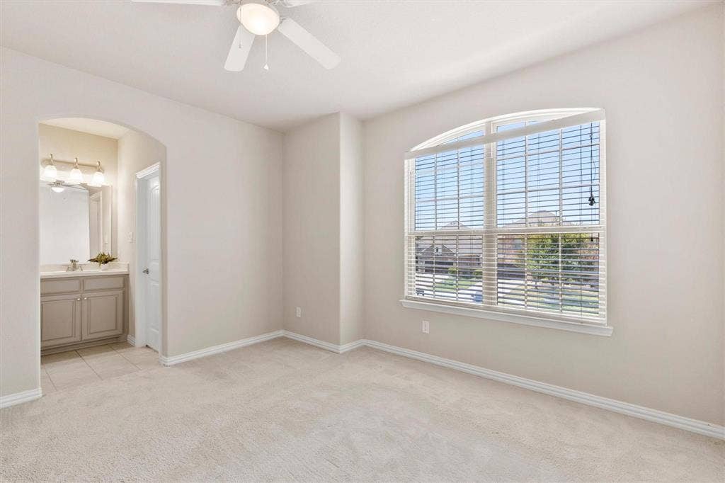 4109 Rainey Street, McKinney, TX 75070 Room featuring neutral wall tones, arched doorway, ceiling fan with light fixture, and a large window with an arched transom