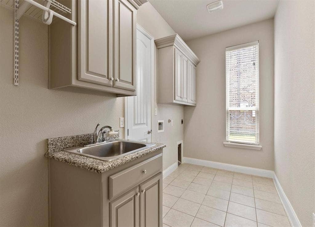 4109 Rainey Street, McKinney, TX 75070 Laundry room featuring tile flooring, stone-finish countertops, stainless steel undermount sink, built-in cabinetry, and a window with horizontal blinds