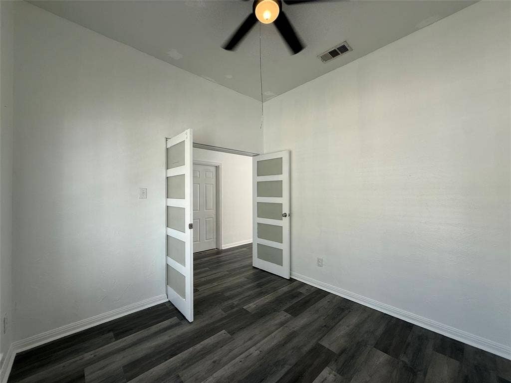 Room featuring vaulted ceilings, wood-finish flooring, and dual French doors with frosted glass inserts, complemented by a ceiling fan