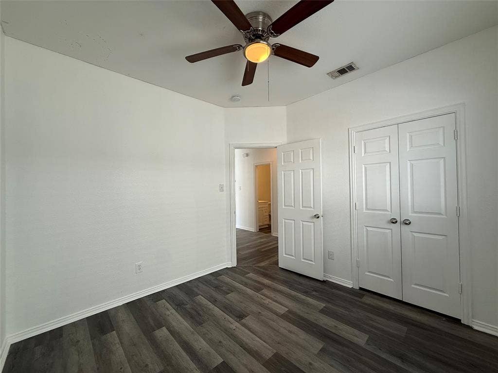 Wood-finish flooring, ceiling fan with integrated lighting, and closet with white paneled double doors