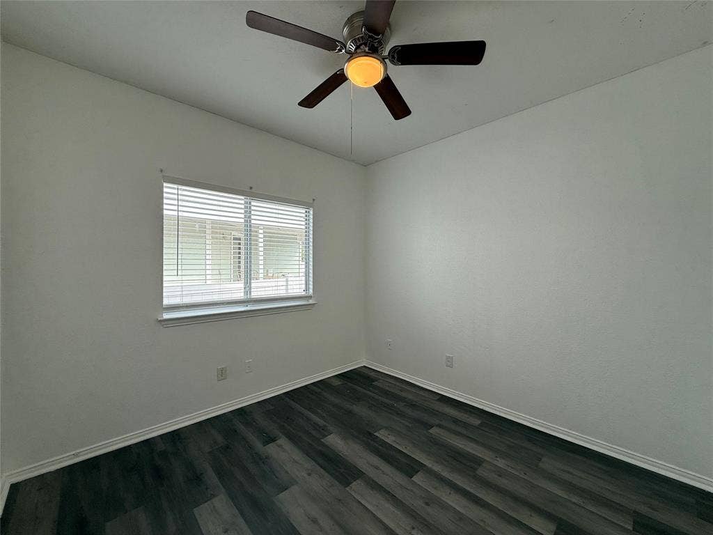 Wood-finish flooring, multi-pane window with horizontal blinds, and ceiling fan with integrated light fixture