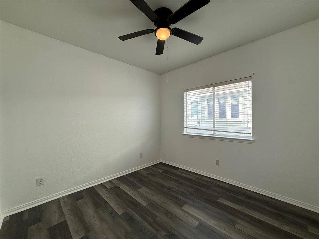 Wood-finish flooring, neutral walls, sliding window with blinds, and ceiling fan with integrated light fixture