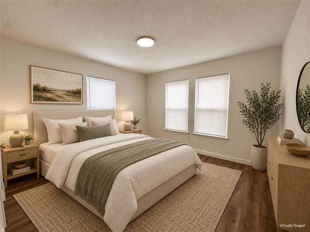 Neutral-toned walls, wood-finish flooring, two dual-pane windows with fitted blinds, and a circular flush-mount ceiling light