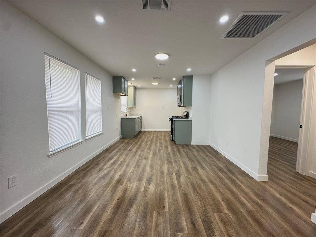 Interior space featuring wood-finish flooring, recessed lighting, and kitchen area with light-colored cabinetry