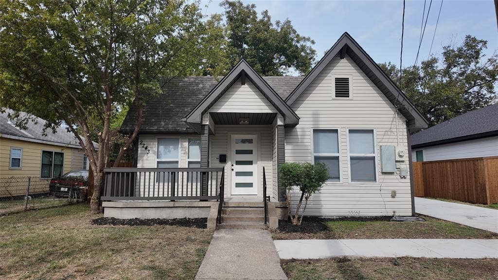 Exterior facade featuring horizontal siding, a gabled roofline, covered front porch with dark railings, and a multi-lite front door