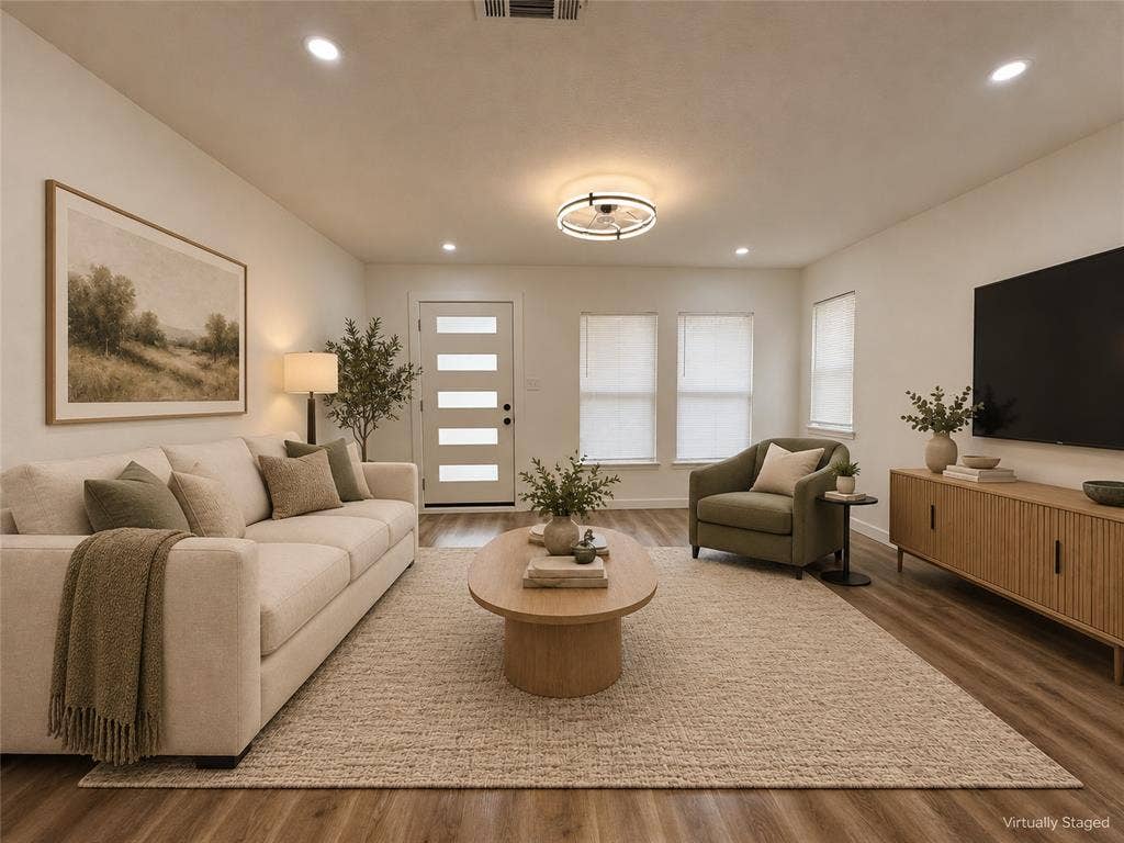 Living area featuring wood-finish flooring, recessed lighting, a modern ceiling-mounted fixture, and a white front door with horizontal glass panels