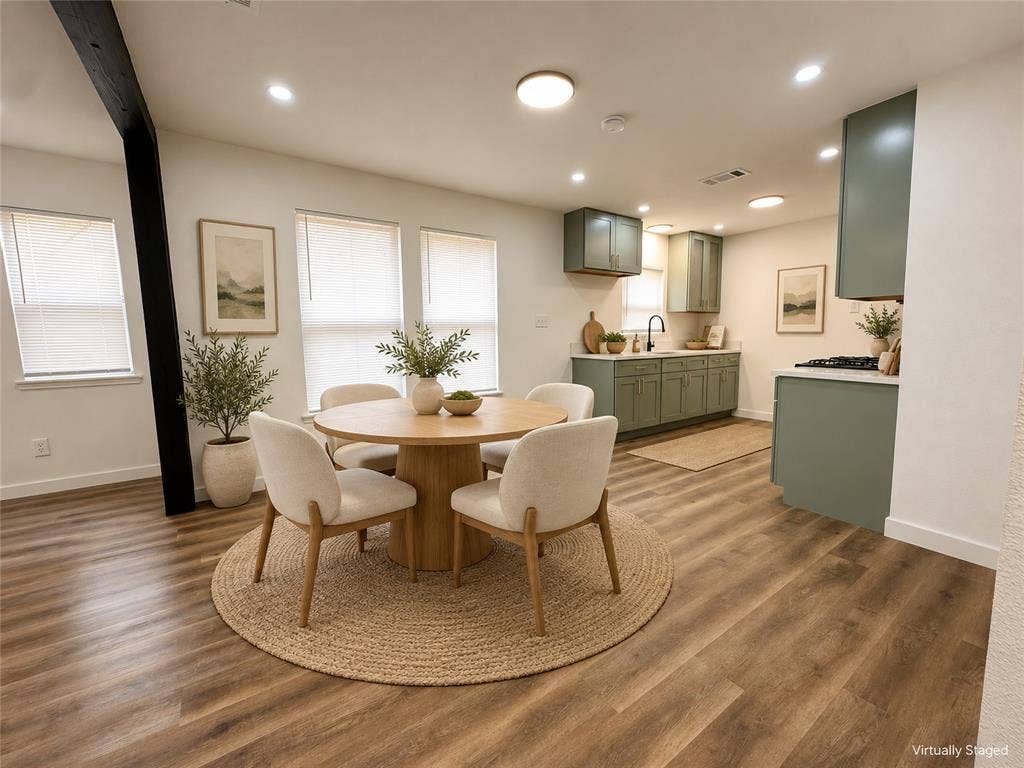 Kitchen featuring sage green cabinetry, light-toned countertops, wood-finish flooring, recessed lighting, and a prominent exposed black structural beam
