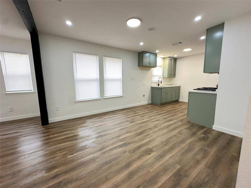 Open-concept space featuring wood-finish flooring, recessed lighting, a structural beam, sage-toned cabinetry, and a gas range