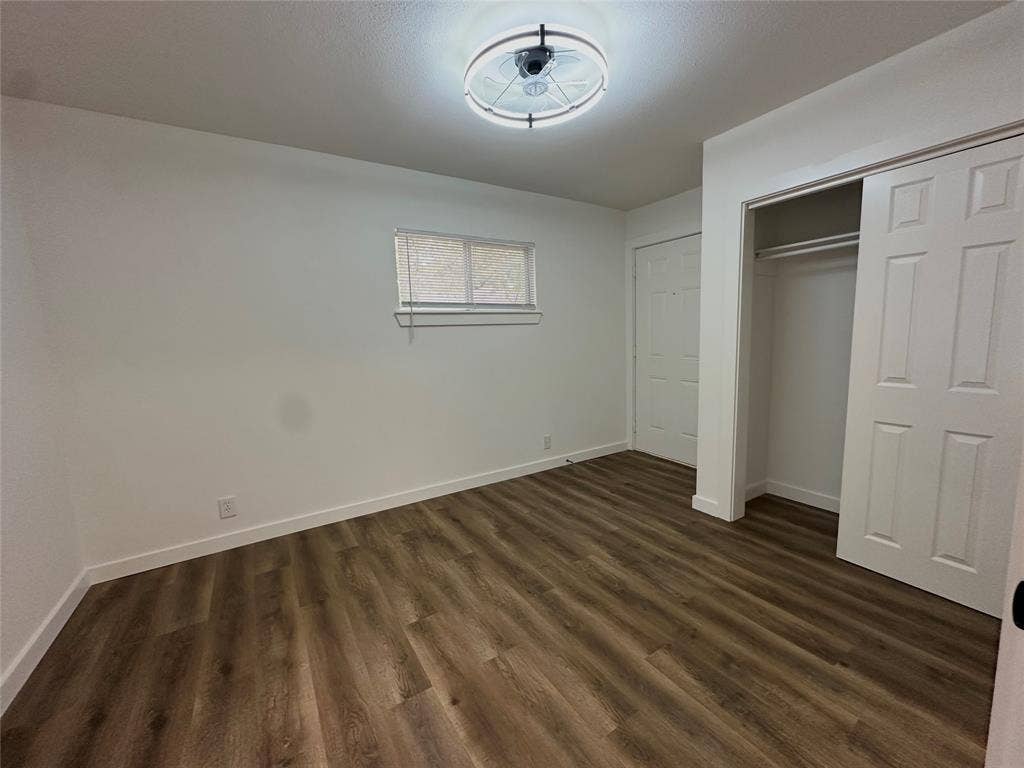 Wood-finish flooring, crisp white walls, sliding closet door, and contemporary circular ceiling light fixture