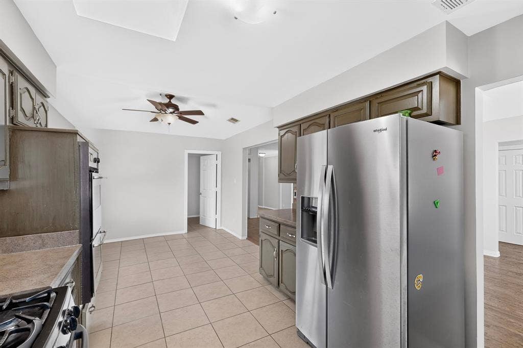 2413 Club Meadow Drive, Garland, TX 75041 Kitchen featuring ceramic tile flooring, upper and lower cabinetry, stainless steel refrigerator, and recessed ceiling