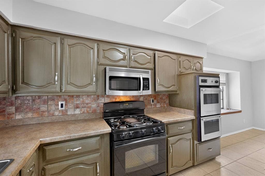 2413 Club Meadow Drive, Garland, TX 75041 Kitchen featuring full-height cabinetry, tile backsplash, built-in stainless steel appliances, and a gas range