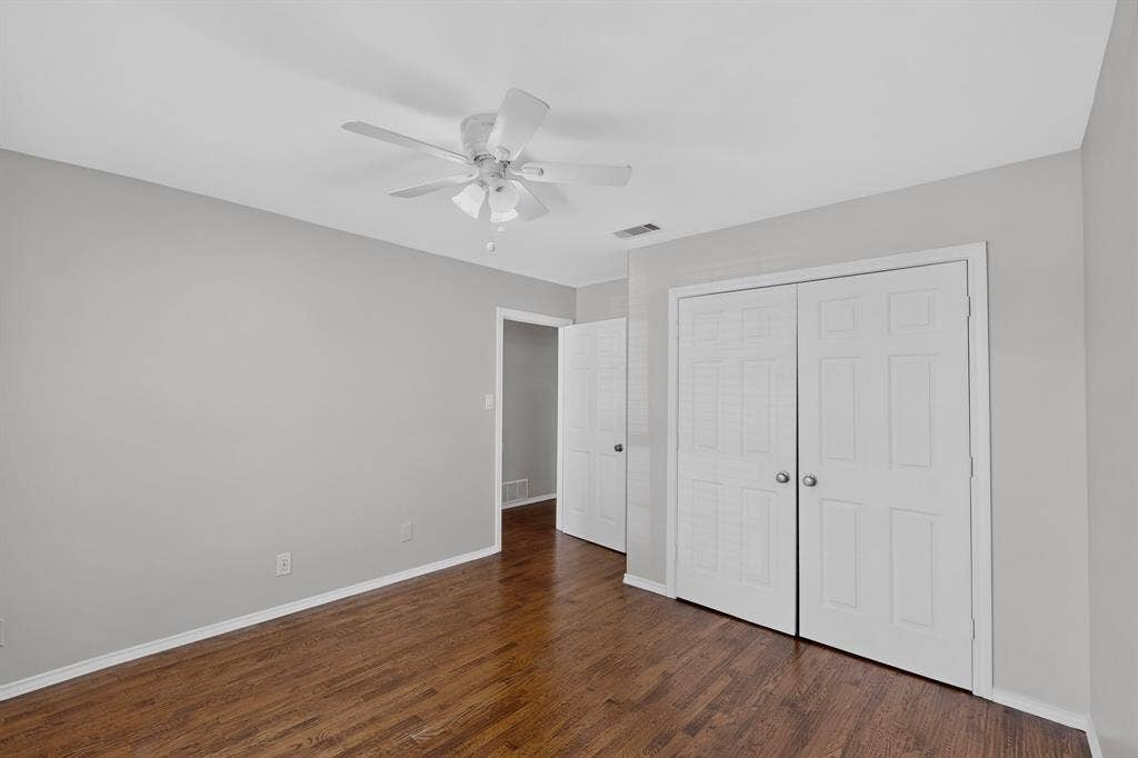 2413 Club Meadow Drive, Garland, TX 75041 Wood-finish flooring, ceiling fan, white bi-fold closet doors, and light-toned walls