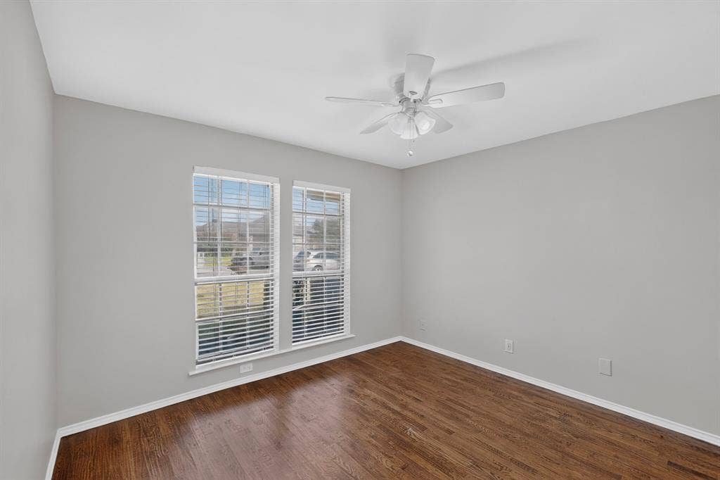 2413 Club Meadow Drive, Garland, TX 75041 Wood-finish flooring, white walls, two windows with blinds, and an overhead ceiling fan with lighting