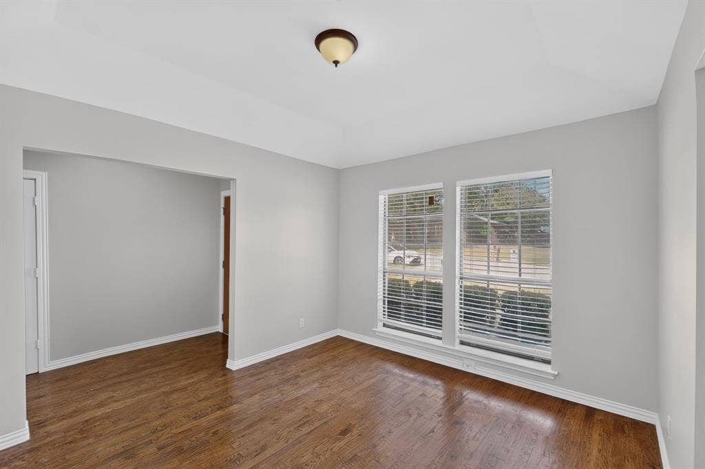 2413 Club Meadow Drive, Garland, TX 75041 Wood-finish flooring, light grey wall paint, and multiple windows with blinds