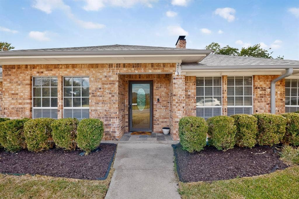 2413 Club Meadow Drive, Garland, TX 75041 Brick exterior with multiple windows, a central entry door with decorative glass, and a concrete walkway