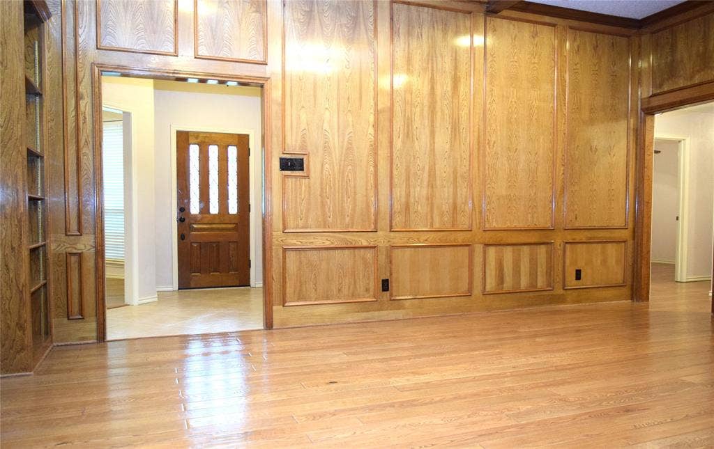 Full-height wood paneling with decorative trim, built-in floor-to-ceiling shelving, and wood-finish flooring