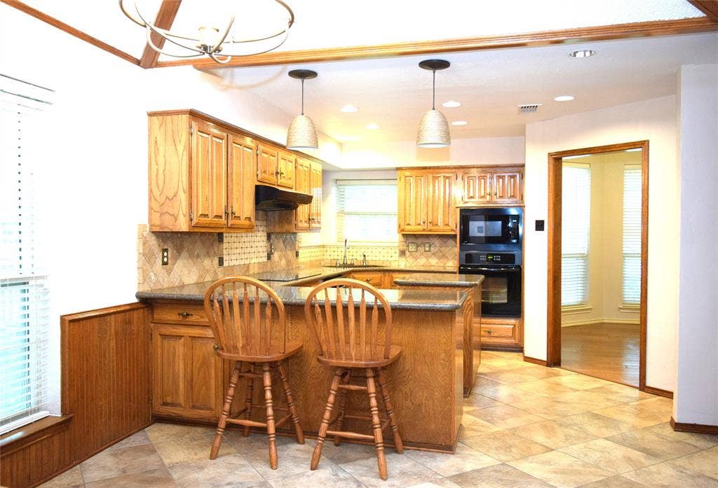 Kitchen featuring wood cabinetry, stone-finish countertops, tile backsplash, built-in wall oven, and ceramic tile flooring