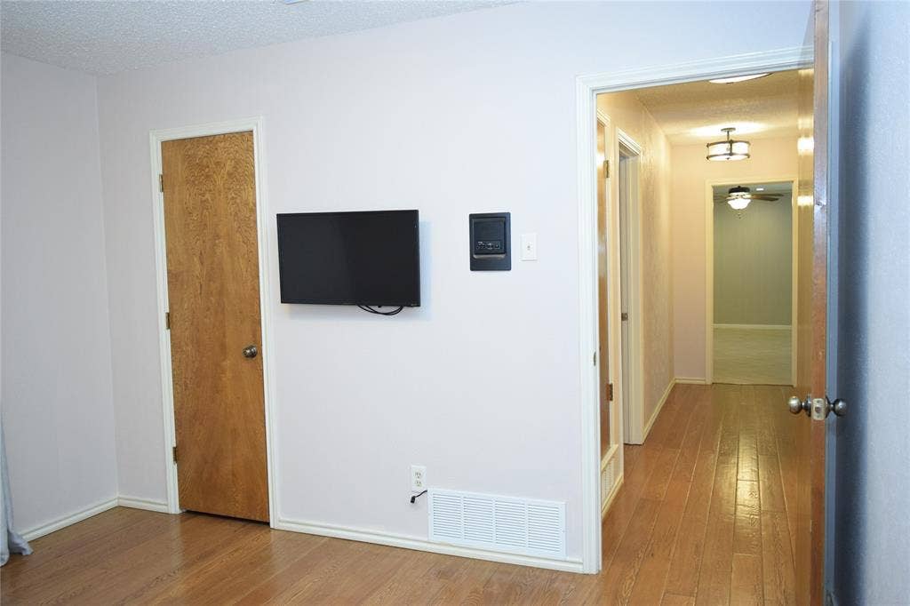 Interior space featuring wood-finish flooring, solid-core doors, and built-in wall-mounted climate control panel