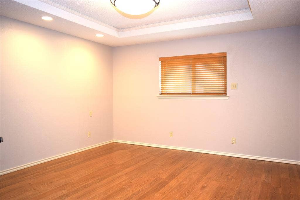 Tray ceiling featuring recessed lighting, wood-finish flooring, and horizontal window blinds