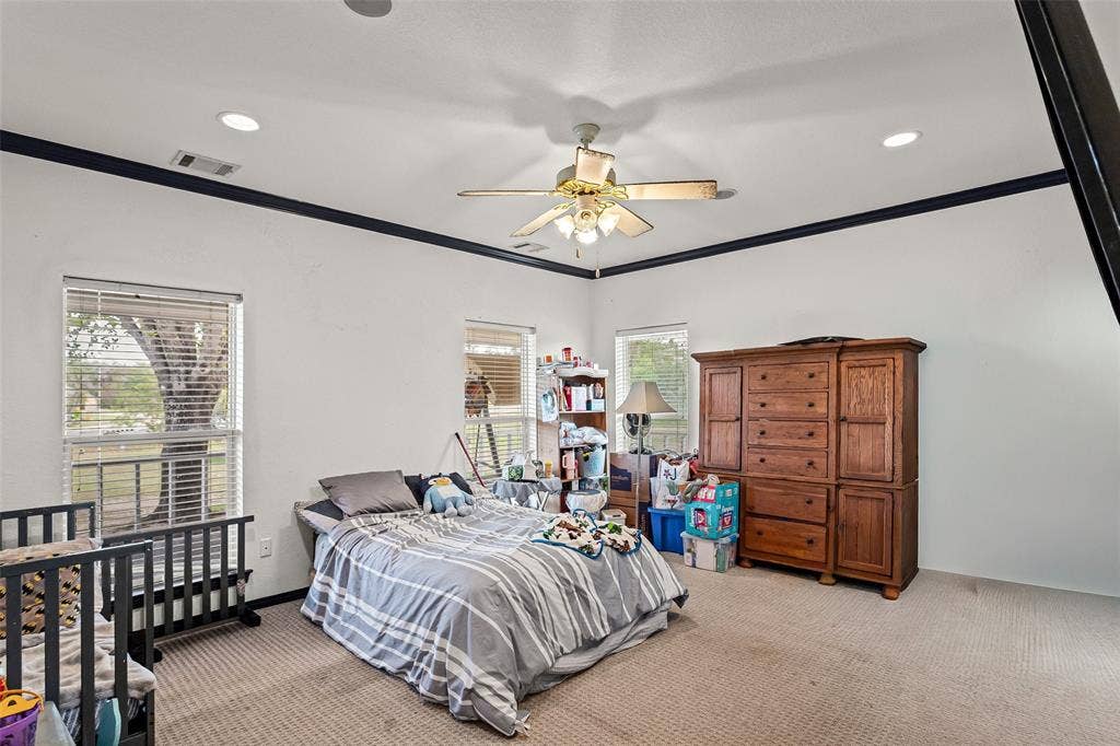 High ceilings featuring dark crown molding, recessed lighting, and a central ceiling fan