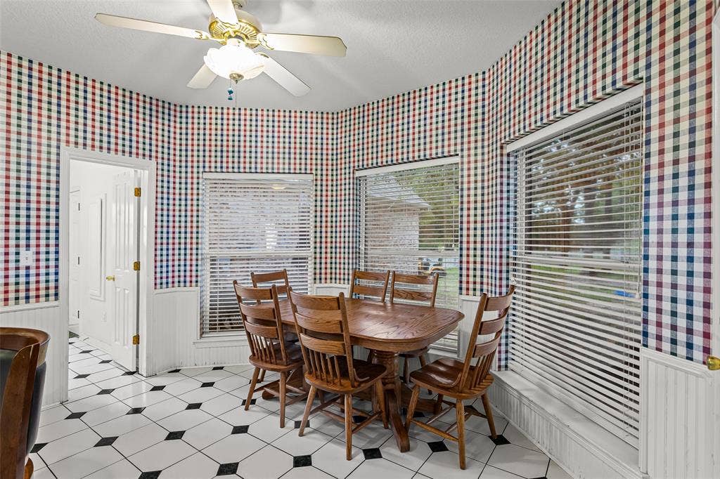 Breakfast nook featuring a bay window configuration, beadboard wainscoting, ceramic tile flooring with a geometric pattern, and a ceiling fan with integrated lighting