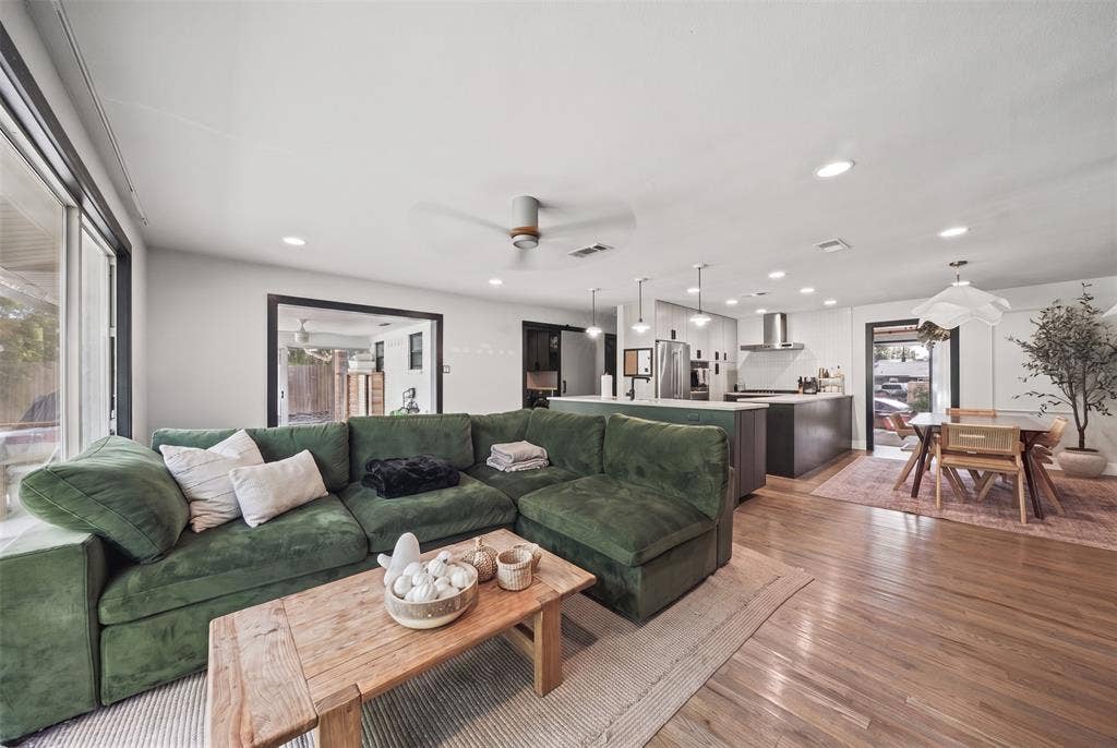 605 Ranier Circle, Garland, TX 75041 Open-concept interior featuring wood-finish flooring, recessed lighting, a modern ceiling fan, and a kitchen equipped with a central island and stainless steel range hood