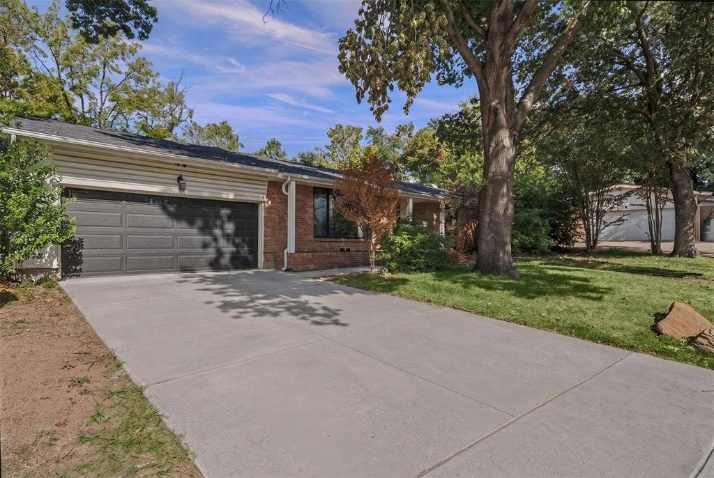 605 Ranier Circle, Garland, TX 75041 Single-story residence featuring a brick and horizontal siding exterior, a concrete driveway, a multi-car garage, and mature trees