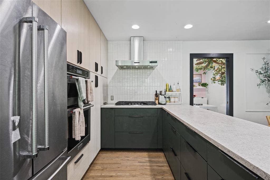 605 Ranier Circle, Garland, TX 75041 Kitchen featuring two-tone cabinetry, stainless steel double wall oven, gas cooktop with stainless steel range hood, stone-finish countertops, and wood-finish flooring