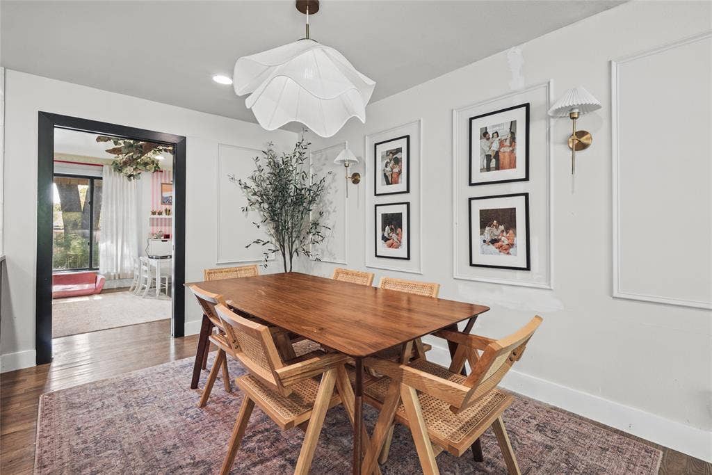 605 Ranier Circle, Garland, TX 75041 Dining area featuring detailed wall molding, wood-finish flooring, a contemporary floral-shaped pendant light, and two brass-finish wall sconces