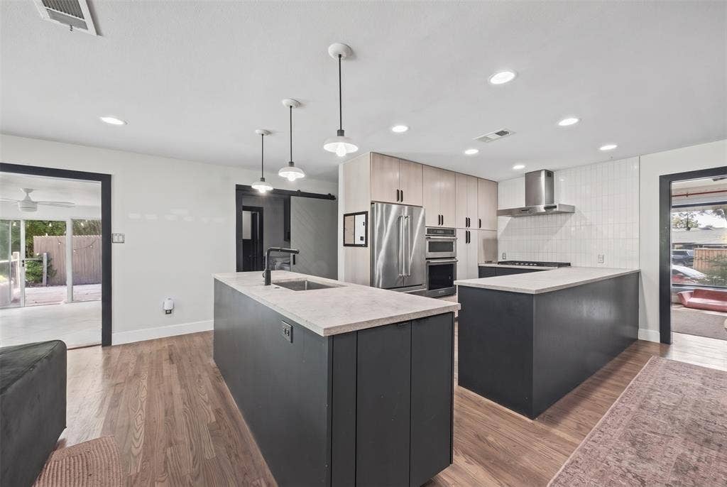 605 Ranier Circle, Garland, TX 75041 Kitchen featuring dual-tone cabinetry, stone-finish countertops, stainless steel appliances, pendant lighting, and wood-finish flooring