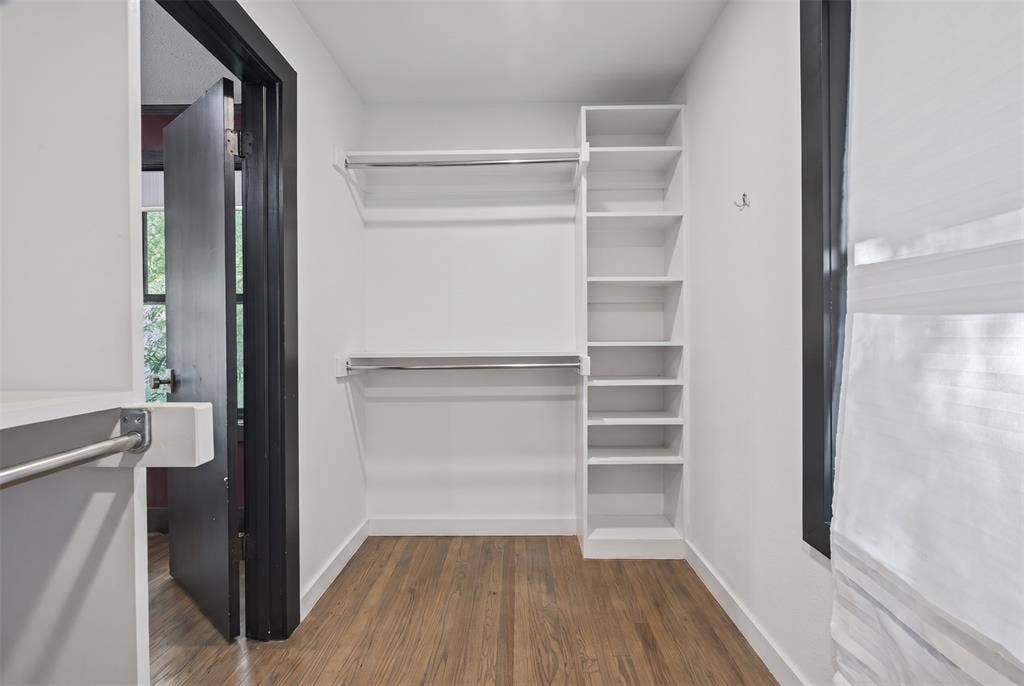 605 Ranier Circle, Garland, TX 75041 Walk-in closet featuring white built-in shelving, dual-tier metal hanging rods, and wood-finish flooring