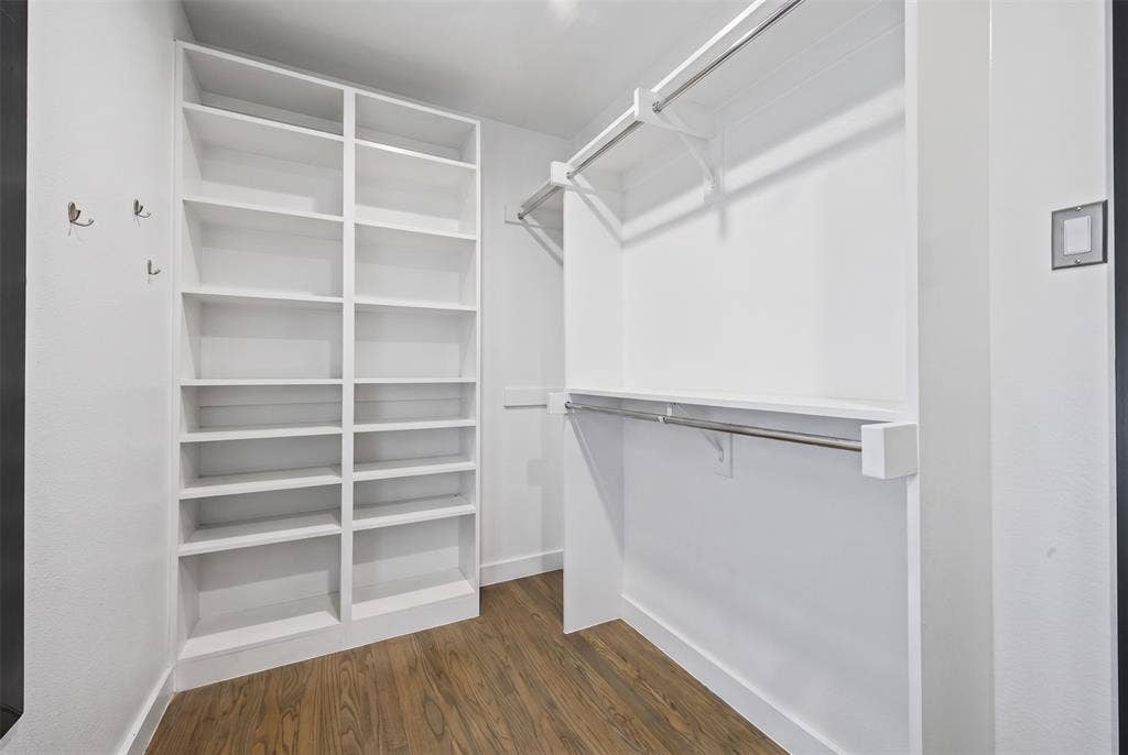 605 Ranier Circle, Garland, TX 75041 Walk-in closet featuring floor-to-ceiling built-in shelving, dual-level hanging rods, wall-mounted hardware hooks, and wood-finish flooring