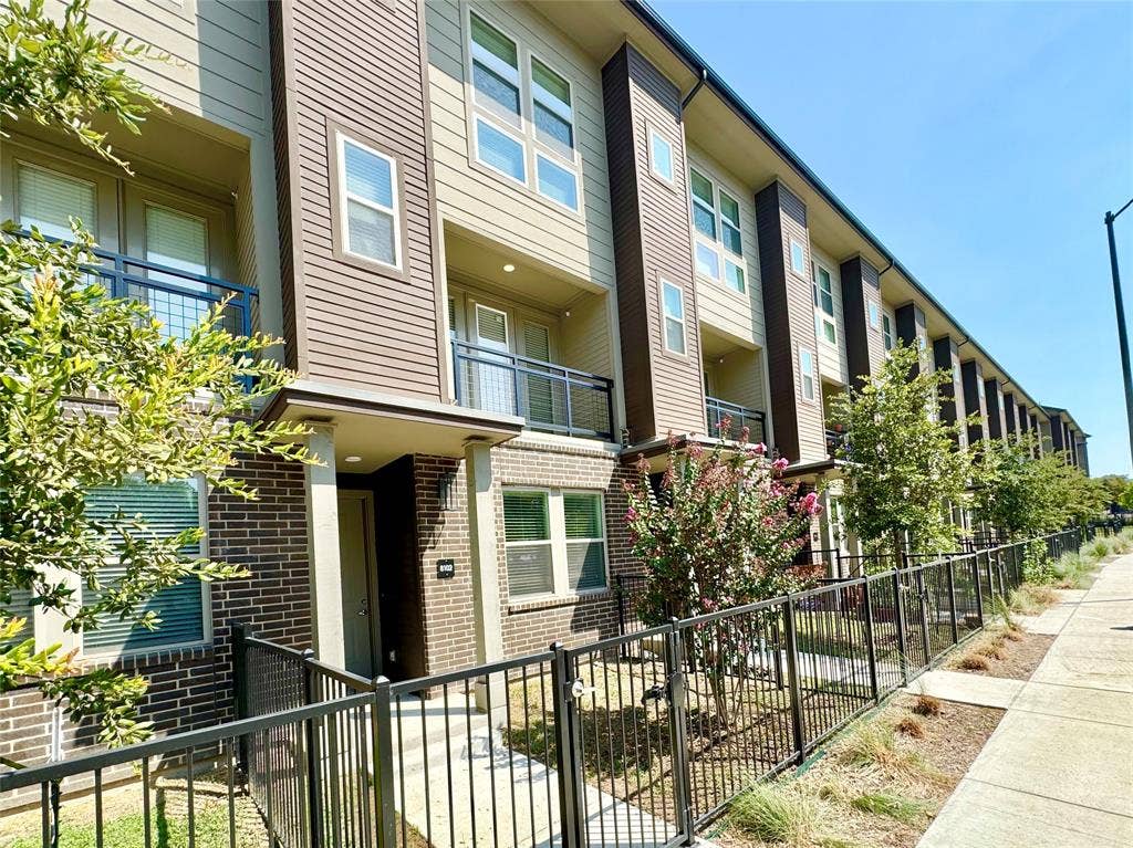 4020 McEwen Road, #4103, Farmers Branch, TX 75244 Multi-level exterior featuring dark brick and horizontal siding, private balconies with metal railings, and a fenced front entry