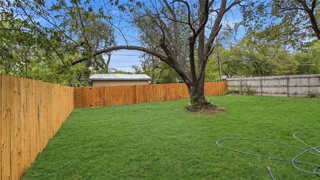 4330 Scottsdale Drive, Mesquite, TX 75150 Expansive backyard featuring a natural grass lawn, mature tree, and full-perimeter wood privacy fencing
